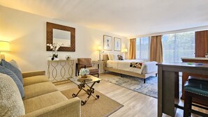 A hotel room with a bed, a sofa, a coffee table, a desk, and a large window with curtains. - A Gem of a Studio at The Diamond Head Beach Hotel (Honolulu)