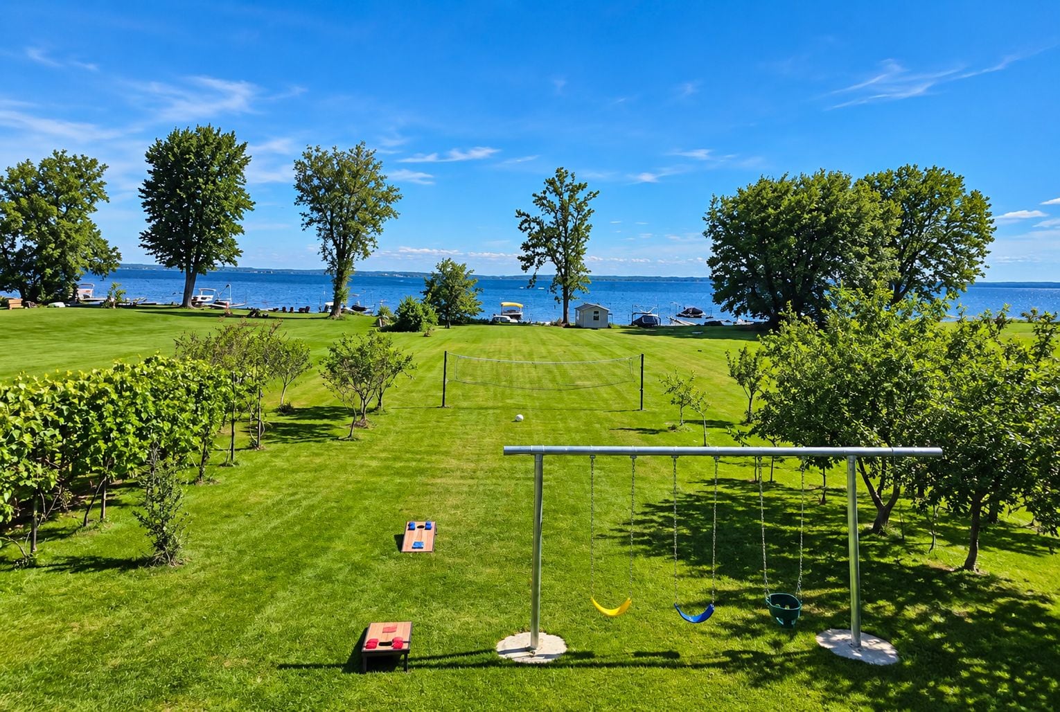 A well-maintained grassy area with a swing set, a small shed, and a view of the sea.