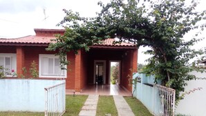 Una casa con techo de tejas rojas, fachada de ladrillo y un porche cubierto.