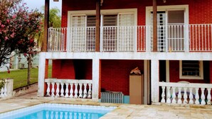 Un edificio de dos pisos con fachada de ladrillo rojo, barandillas blancas y una antena parabólica.