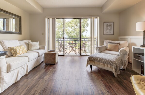 A spacious living room with two sofas, a coffee table, and a balcony with a table and chairs.