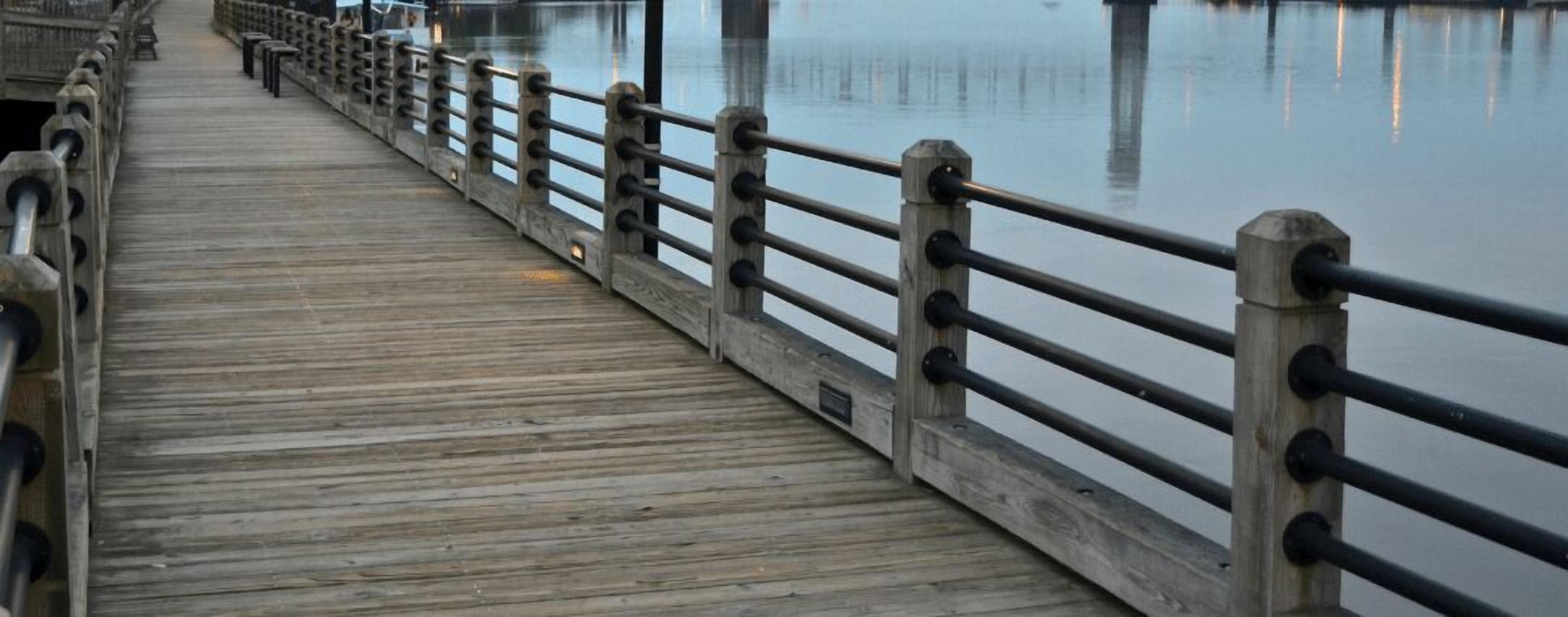 A wooden pier with railings extending over calm water.