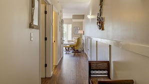 Un pasillo con suelo de madera, un banco y una puerta que da a una habitación.