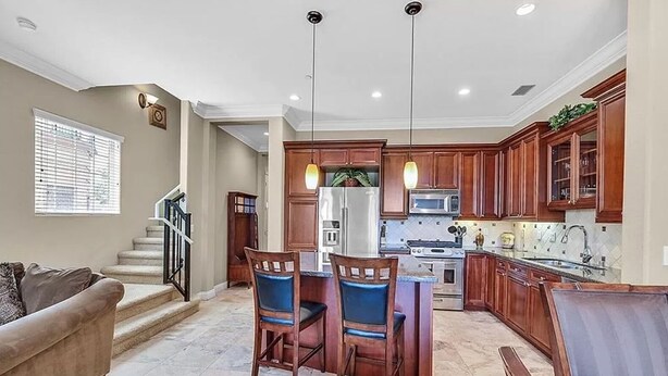 A spacious kitchen with wooden cabinets, a central island, and pendant lighting. - Condo at  Prestigious gated V community (Henderson)