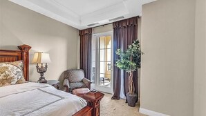 A hotel room with a large bed, a chair, a lamp, a potted plant, and a view of the outdoors. - Condo at  Prestigious gated V community (Henderson)