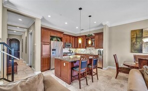 Una cocina amplia con armarios de madera, una isla central con taburetes y un comedor con mesa y sillas.