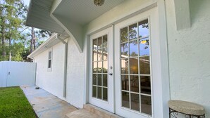 A house with a white exterior, a covered porch, and a small outdoor seating area. - Cheerfull Villa..  Best Location in Naples!!!  All you need in one home. (Naples)