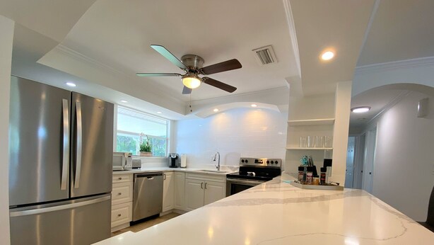 A modern kitchen with stainless steel appliances, white cabinetry, and a large island. - Cheerfull Villa..  Best Location in Naples!!!  All you need in one home. (Naples)
