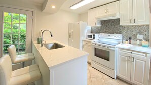 A modern kitchen with white cabinetry, a built-in oven, microwave, and a large island with a sink. - Cheerfull Villa..  Best Location in Naples!!!  All you need in one home. (Naples)