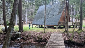A wooden bridge leading to a cabin in a forested area. - Private Rustic A-Frame in the Heart of Elk Country (Benezette)