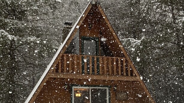 A wooden cabin with a balcony, surrounded by snow-covered trees. - Private Rustic A-Frame in the Heart of Elk Country (Benezette)