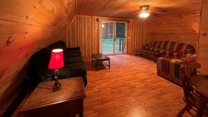 A cozy wooden interior with a sofa, a table, and a lamp. - Private Rustic A-Frame in the Heart of Elk Country (Benezette)