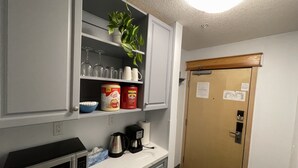 A kitchenette with a microwave, coffee maker, and storage cabinets.