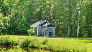 Un piccolo chalet con veranda, immerso nel verde e con uno stagno.