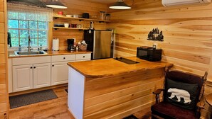 Una cucina compatta con pareti in legno, un frigorifero in acciaio inossidabile, un forno a microonde e un lavandino.