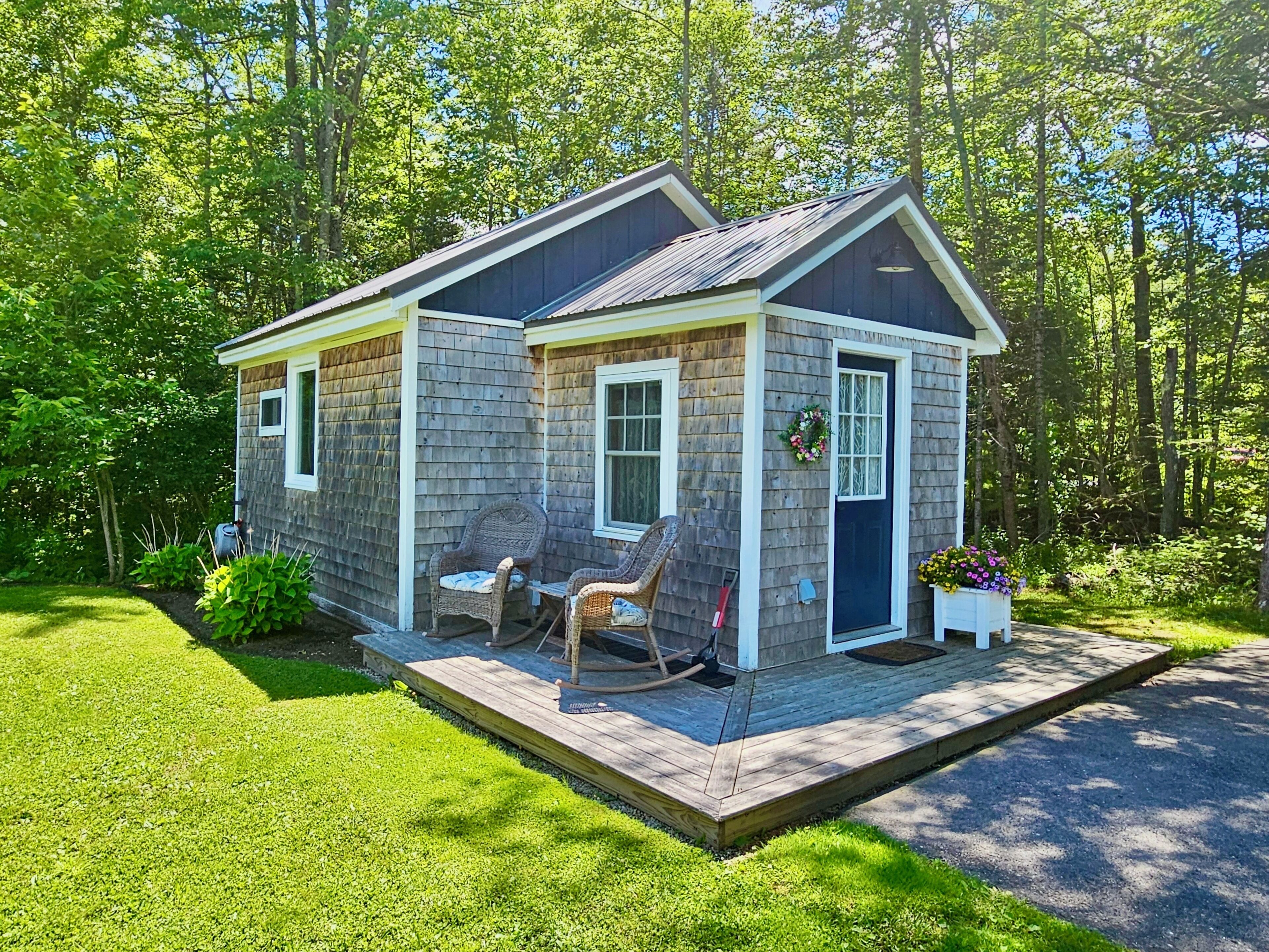 A small wooden cabin with a porch, two rocking chairs, and a flower box.
