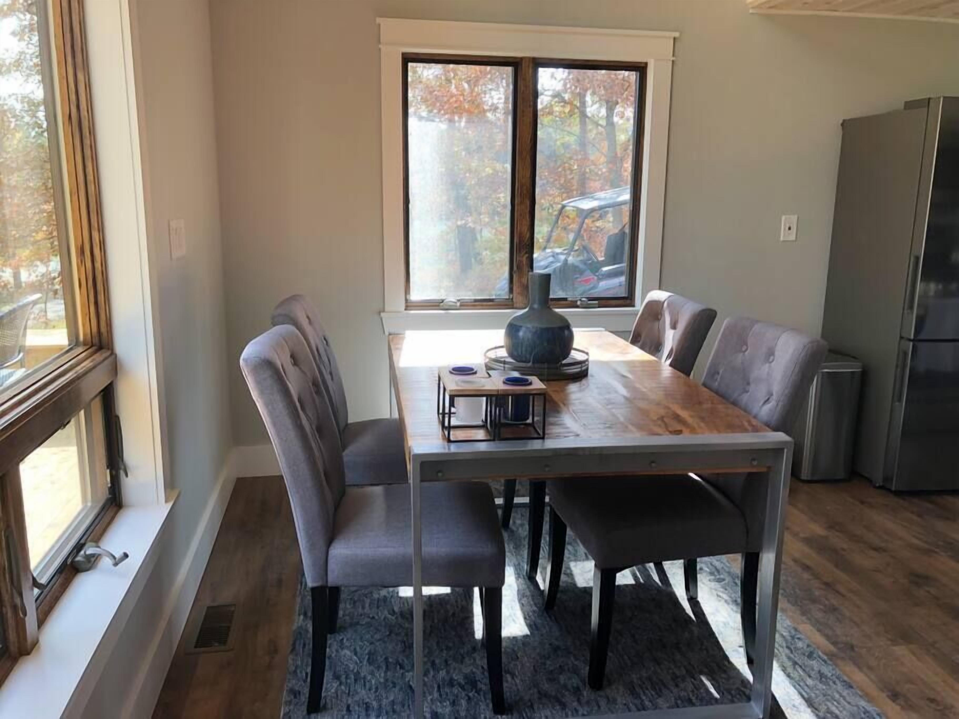 A dining area with a wooden table and four grey upholstered chairs.