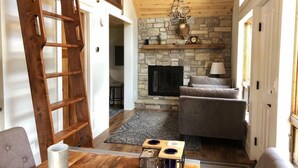 Ein gemütliches Wohnzimmer mit Kamin aus Stein, Holzboden und einem Essbereich mit Tisch und Stühlen.