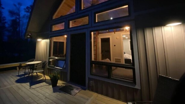 Ein modernes Haus mit einer Terrasse, großen Fenstern und einer Tür, die zu einem Raum führt.