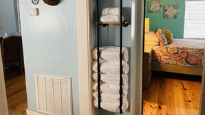 Een kamer met een handdoekrek, een radiator, een bed met een kleurrijke sprei en een wand met een mand en een fietsdecoratie.
