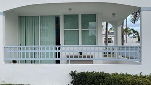 A white building with a balcony featuring a white railing and a potted plant. - Cozy Apartment in the Heart of Rincon (Rincon)