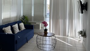 A living room with a blue sofa, a round coffee table, and a TV mounted on the wall. - Cozy Apartment in the Heart of Rincon (Rincon)