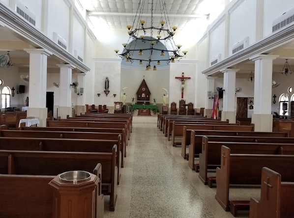 L’intérieur d’une église avec des bancs en bois, un autel central et un lustre.