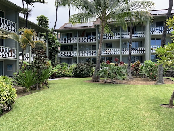 A multi-story hotel with balconies, lush landscaping, and a well-maintained lawn.