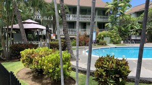 A pool area with a clear view of the pool, surrounded by well-maintained grass and tropical plants. - Poolside Cozy 1br, 1Qbed plus 1QSofa bed, Med refrig, sm kitchen,2min to Ocean (Kailua-Kona)