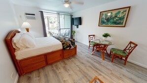 A bedroom with a bed, a table with chairs, a painting, and a ceiling fan. - Poolside Cozy 1br, 1Qbed plus 1QSofa bed, Med refrig, sm kitchen,2min to Ocean (Kailua-Kona)