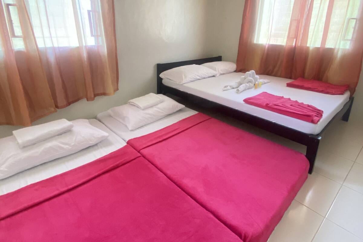 A room with two beds, each with a red bedspread and white pillows.