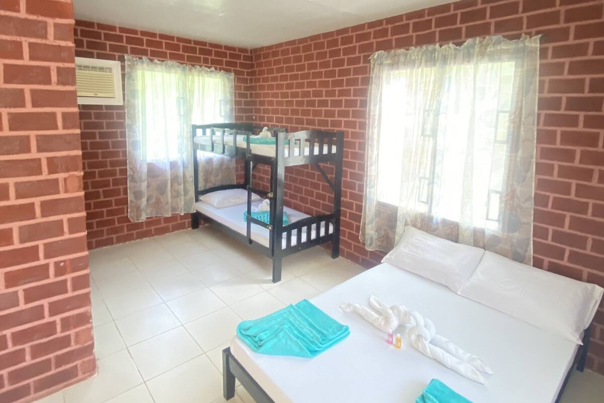A room with two bunk beds, a single bed, a ceiling fan, and a window with curtains.