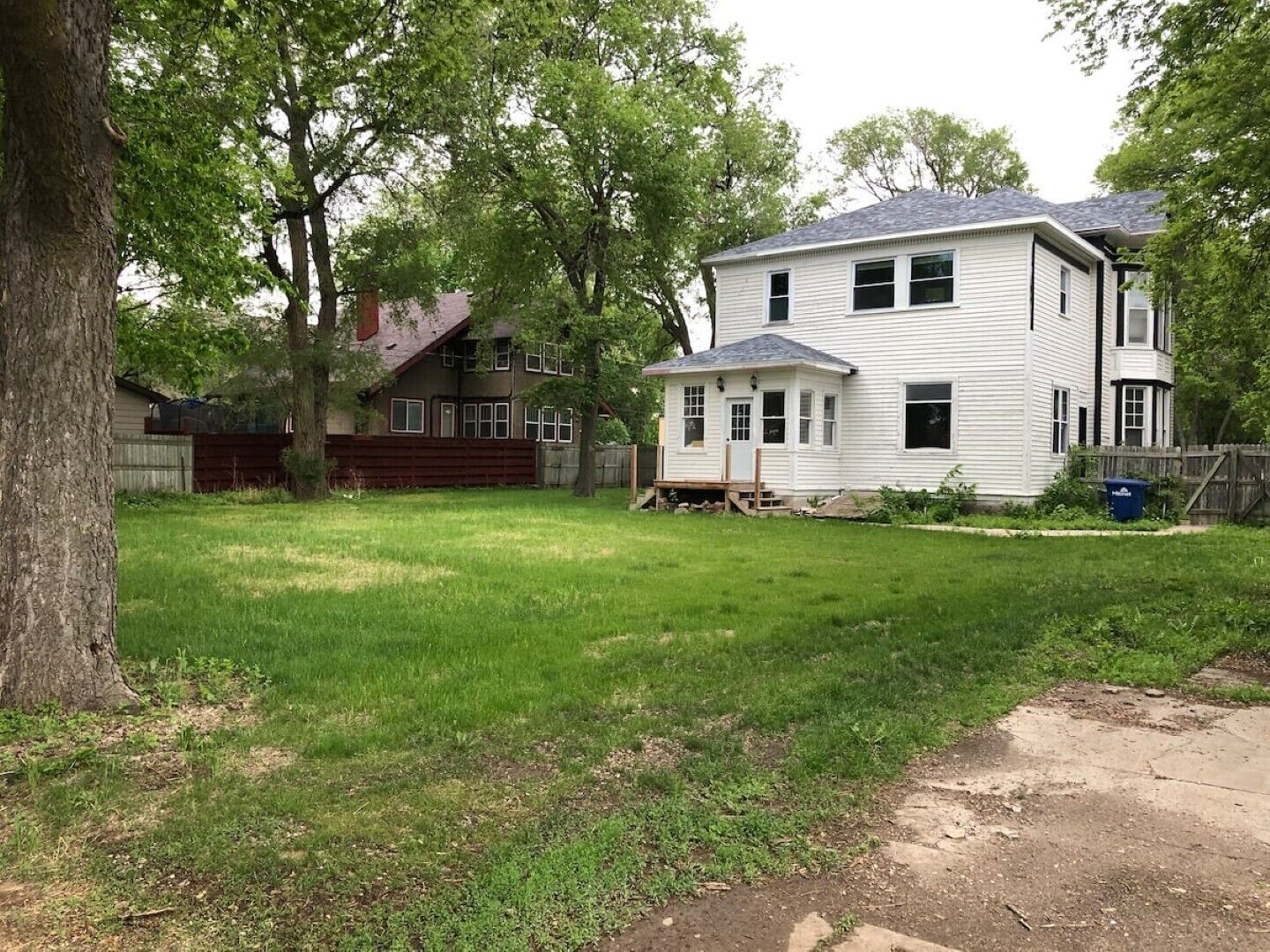 A two-story house with a front yard and a wooden fence.