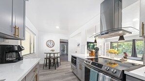 A modern kitchen with a central island, stainless steel appliances, and a view of the outdoors.
