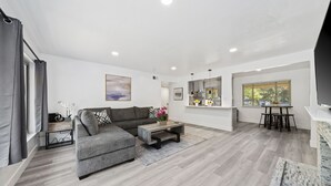 A modern living room with a grey sectional sofa, a coffee table, and a dining area with a table and chairs.