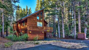 A wooden cabin with a balcony, surrounded by tall trees. - Fully updated Truckee cabin with plenty of beds (Truckee)