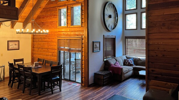 A wooden interior with a dining area, a large wall clock, and a cozy seating area. - Fully updated Truckee cabin with plenty of beds (Truckee)