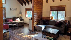 A cozy log cabin interior with a wooden ceiling, a sofa, a coffee table, and a sign that reads "FAMILY". - Fully updated Truckee cabin with plenty of beds (Truckee)