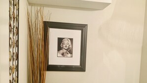 Een badkamer met een toilet, een ingelijste foto aan de muur en een decoratieve vaas met hoge rietstengels.