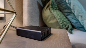 Un haut-parleur portable noir, posé sur une surface en bois, avec un cadre métallique sur le côté gauche.