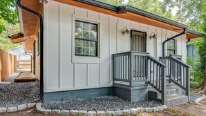 Une maison avec un porche, un escalier et un petit jardin.
