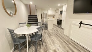 Una cocina moderna con armarios blancos, un refrigerador de acero inoxidable y un horno empotrado.