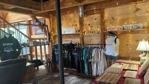 A rustic wooden interior with a clothing rack, a mannequin, and a table with wooden boxes. - Base Camp Glamping @ Hidden Ridge (Saint Johnsbury)
