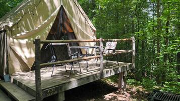 A tent with a fire safety sign, a wooden deck, and two chairs.
