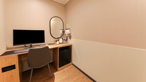 A hotel room with a wooden desk, a computer, a chair, a coffee maker, and a mirror. - Hound Hotel Sasang (Busan)