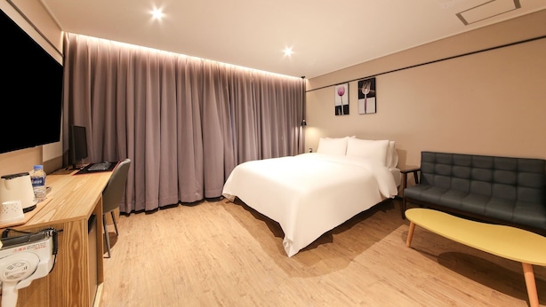 A hotel room with a bed, a desk with a computer, a chair, a sofa, and a small table. - Hound Hotel Sasang (Busan)
