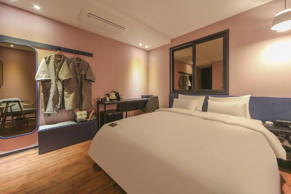 Ein Hotelzimmer mit einem Bett, einem Schreibtisch, einem Stuhl, einem Spiegel und einem Kleiderschrank.
