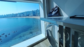 A room with a large window overlooking a beach and city skyline. - Ocean the point Hotel (Busan)
