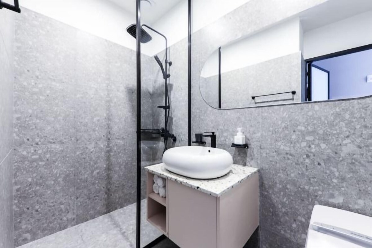 A modern bathroom with a freestanding shower, a white sink, and a large mirror.