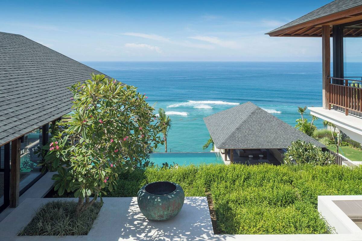 A resort with a view of the ocean, a large vase, and a well-maintained garden.